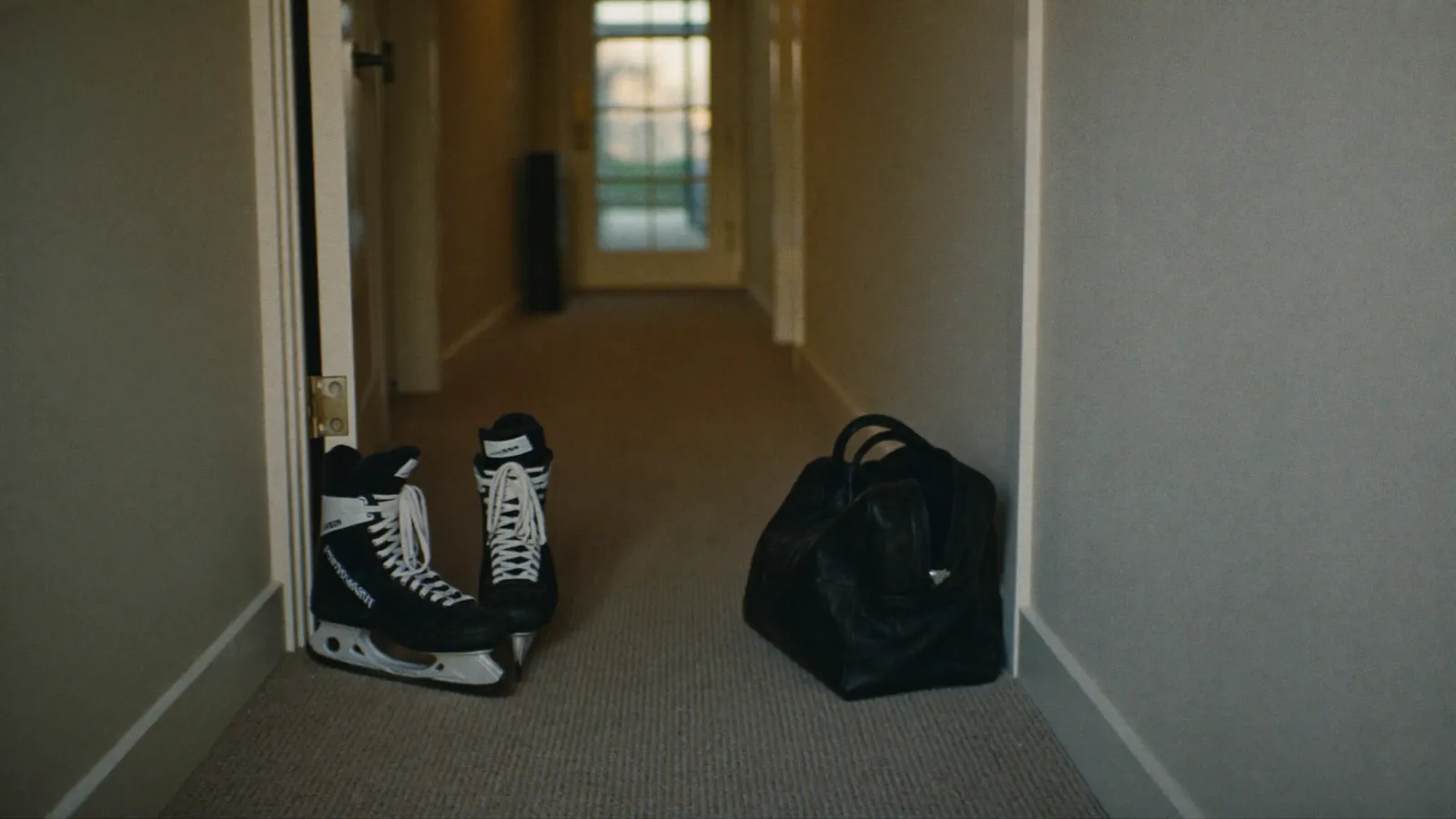 A pair of hockey skates and a gear bag on the carpet outside a hotel room door